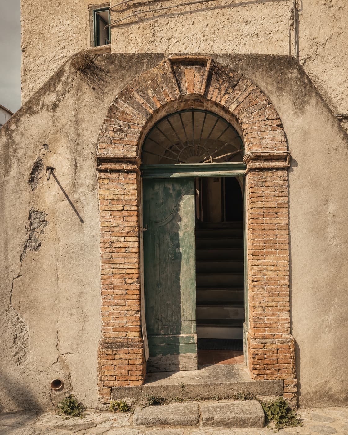A half-open doorway in Ravello, brick archway and a staircase leading up inside — the first conversation, before anything is decided.
