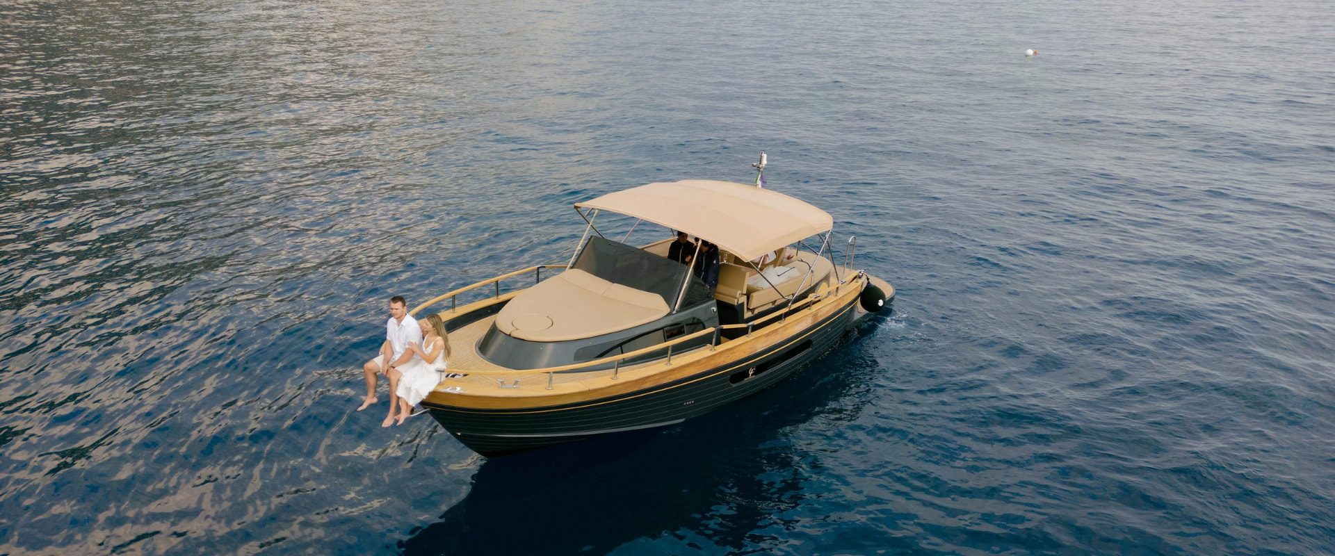 A couple sitting on the bow of my boat, anchored off the coast